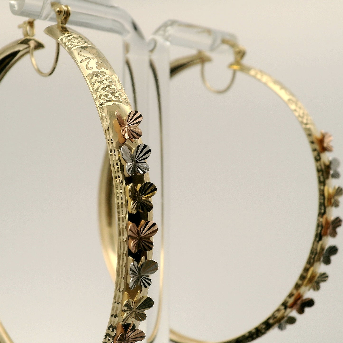 Arracadas texturizadas de oro amarillo con mariposas tricolor.